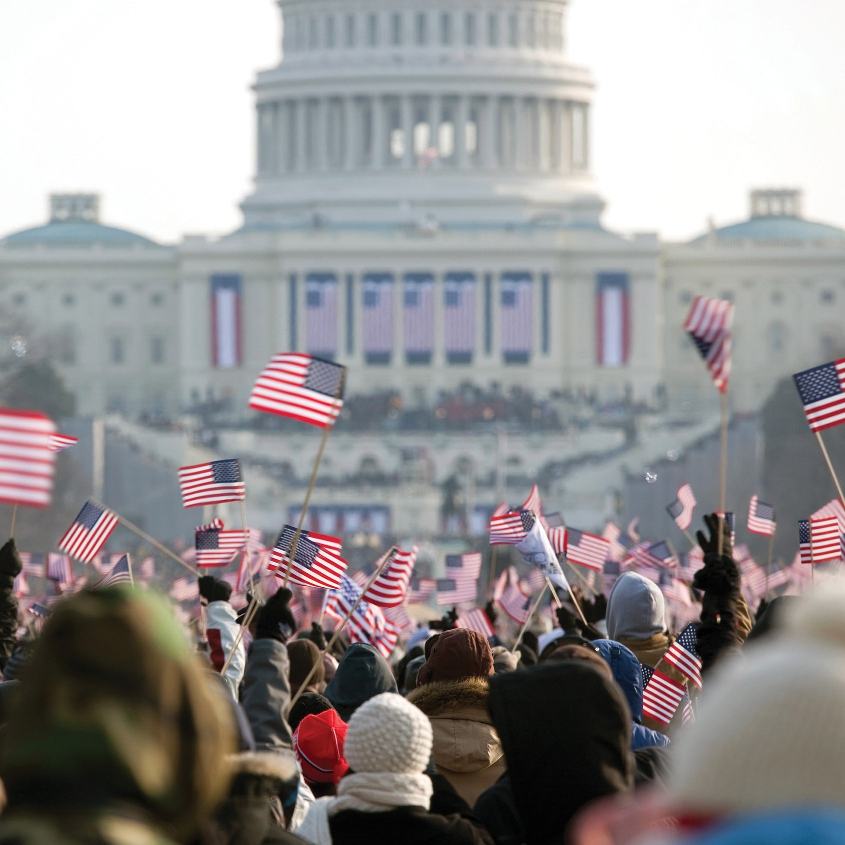 Picture of those attending inauguration, holding mini United States flags infront of the capitol building in Washington, DC.